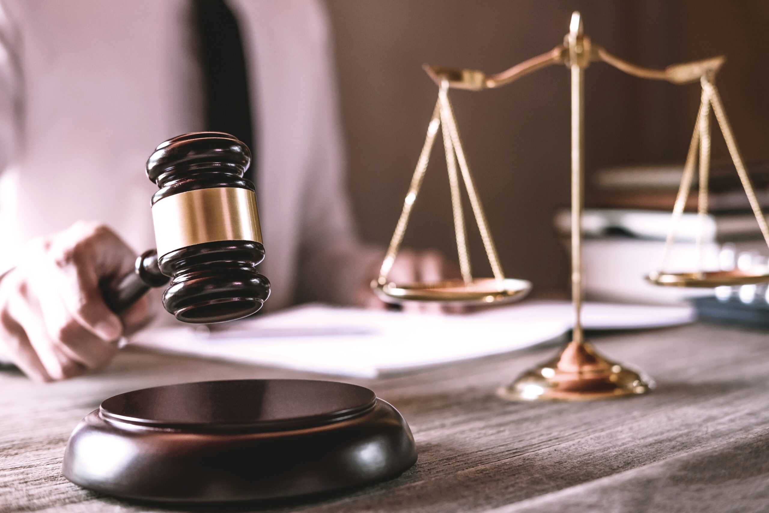 Gavel on wooden table and Lawyer or Judge working with agreement in Courtroom theme, Justice and Law concept.